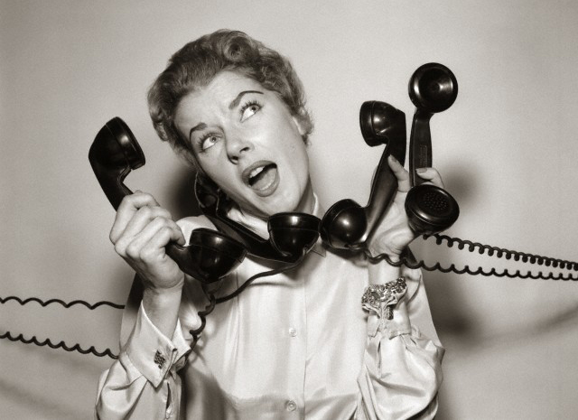 1950s 1960s Overwhelmed Stressed Woman Answering Four Black Telephone Phone Receivers At One Time